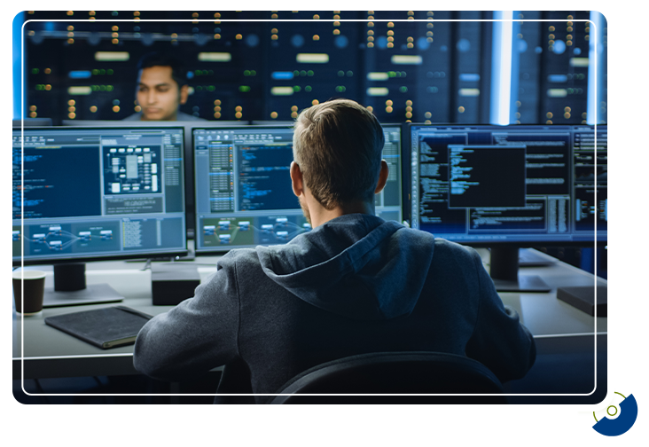 an engineer looking at a bank of computer monitors and analyzing data
